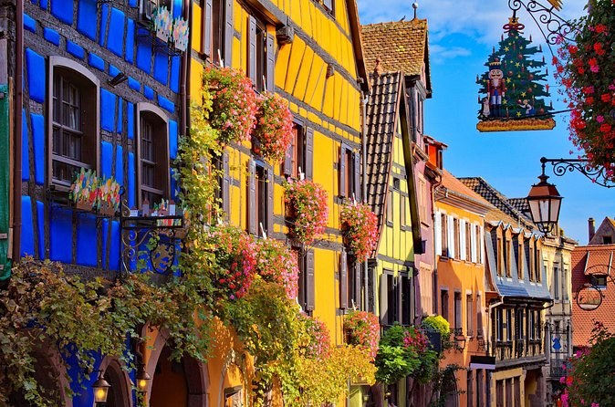 Blue and yellow house fronts with a painted Christmas-tree sign over the street