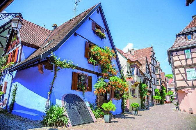 A blue house front hung with flowers on a village street