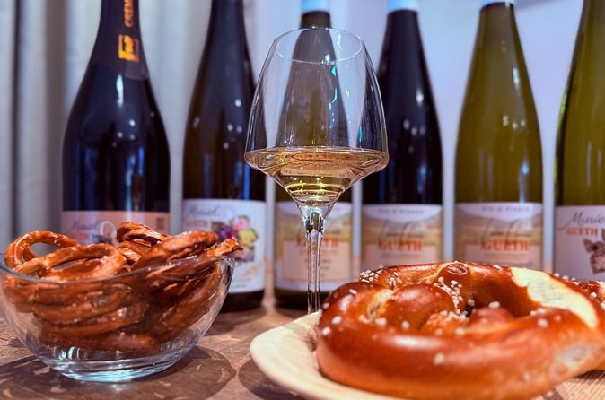 Alsace bottles and a poured glass behind a basket of pretzels