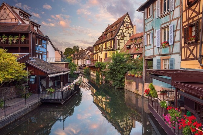 Colmar's Little Venice at dusk, the painted houses doubled in the still canal