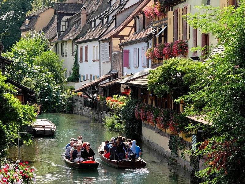 Flat-bottomed punts on the canal through Colmar's Little Venice, between half-timbered houses