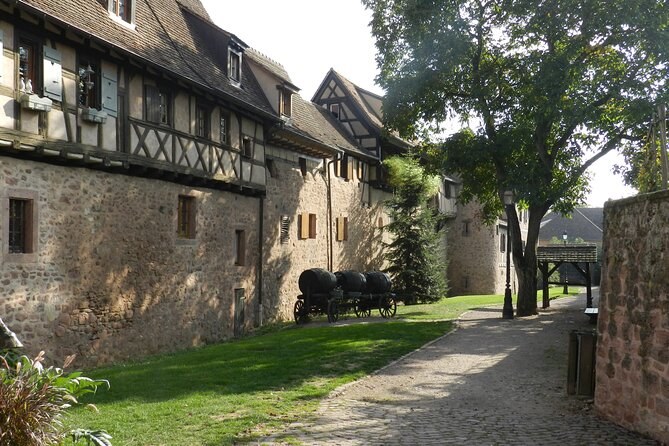 An old town wall with half-timbered houses on top, a grass path along its foot