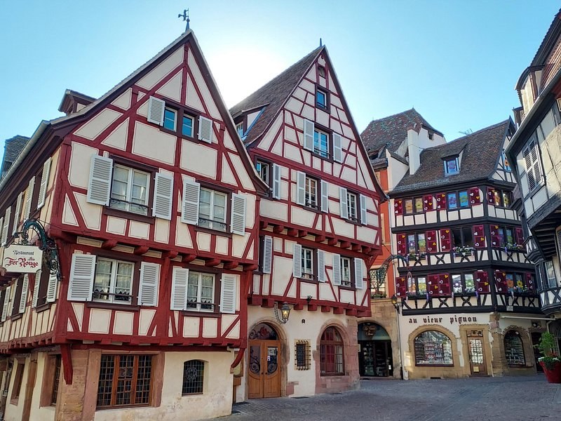 Tall red and white half-timbered fronts on a cobbled square