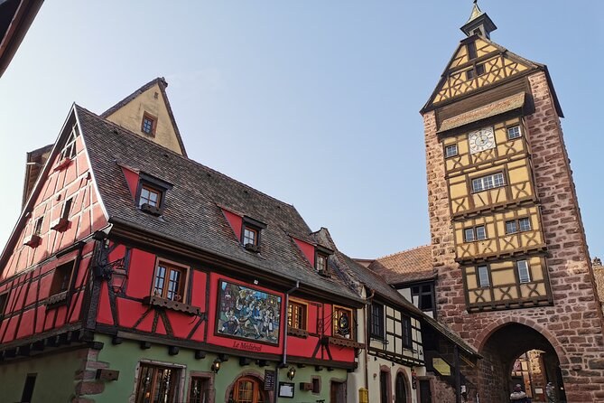 Riquewihr's Dolder gate tower beside a painted red house front